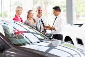 vehicle salesman showing new car to a family